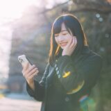 スマホを見て微笑む女性の画像